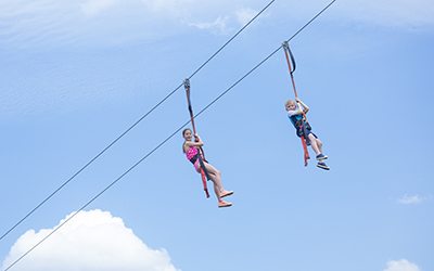 Two kids playing on a zip line view from below view of kids ziplining