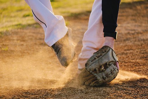 Baseball player action shot on field with ball and glove in dirt