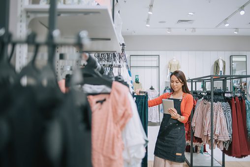 Female retail worker reviewing products in clothing store