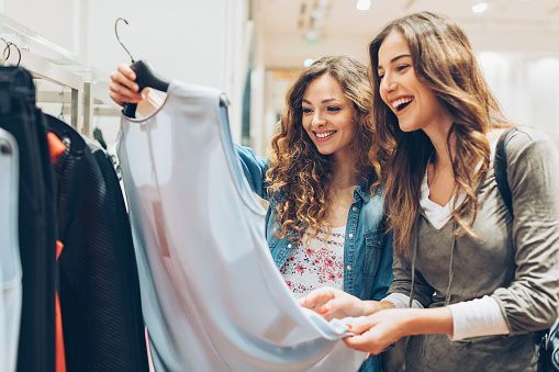 Two cheerful girls shopping for clothes