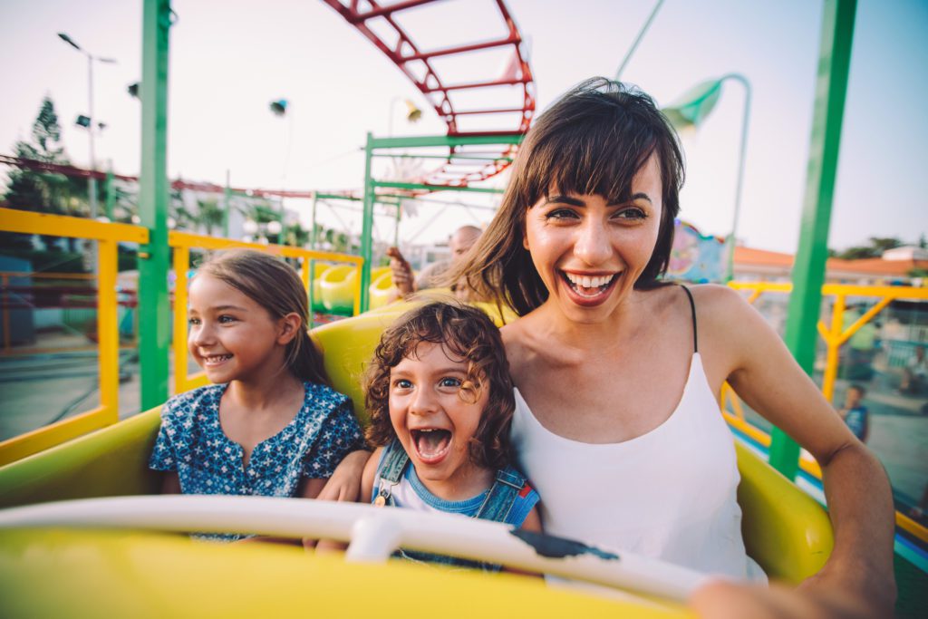 a mom and two kids enjoying one of the rides at an amusement park near myrtle beach