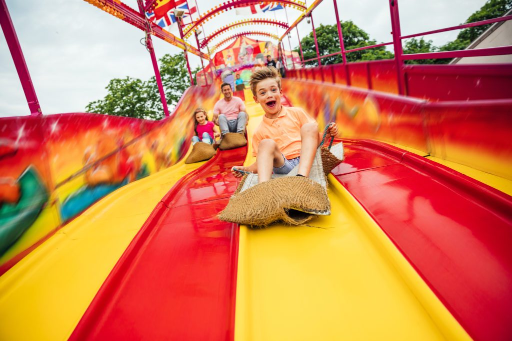 a dad and his two kids sliding down the giant slide at the pavilion nostalgia park. 